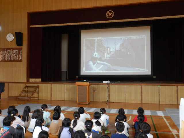 スクリーンに交通安全のDVDを映写し交通ルールを学ぶ3年生